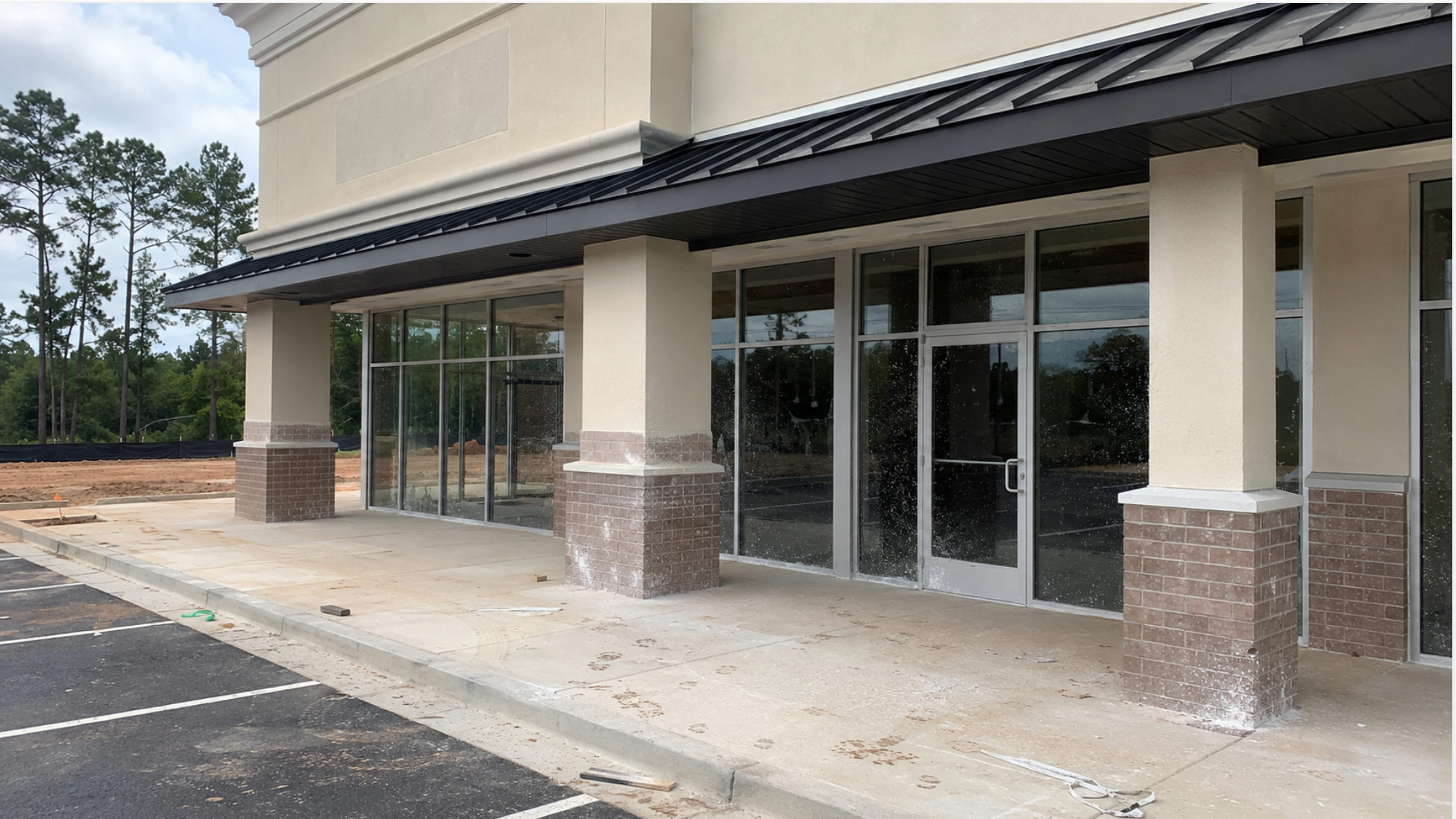 Newly built commercial site with construction dust, debris, and window film on entries and facade