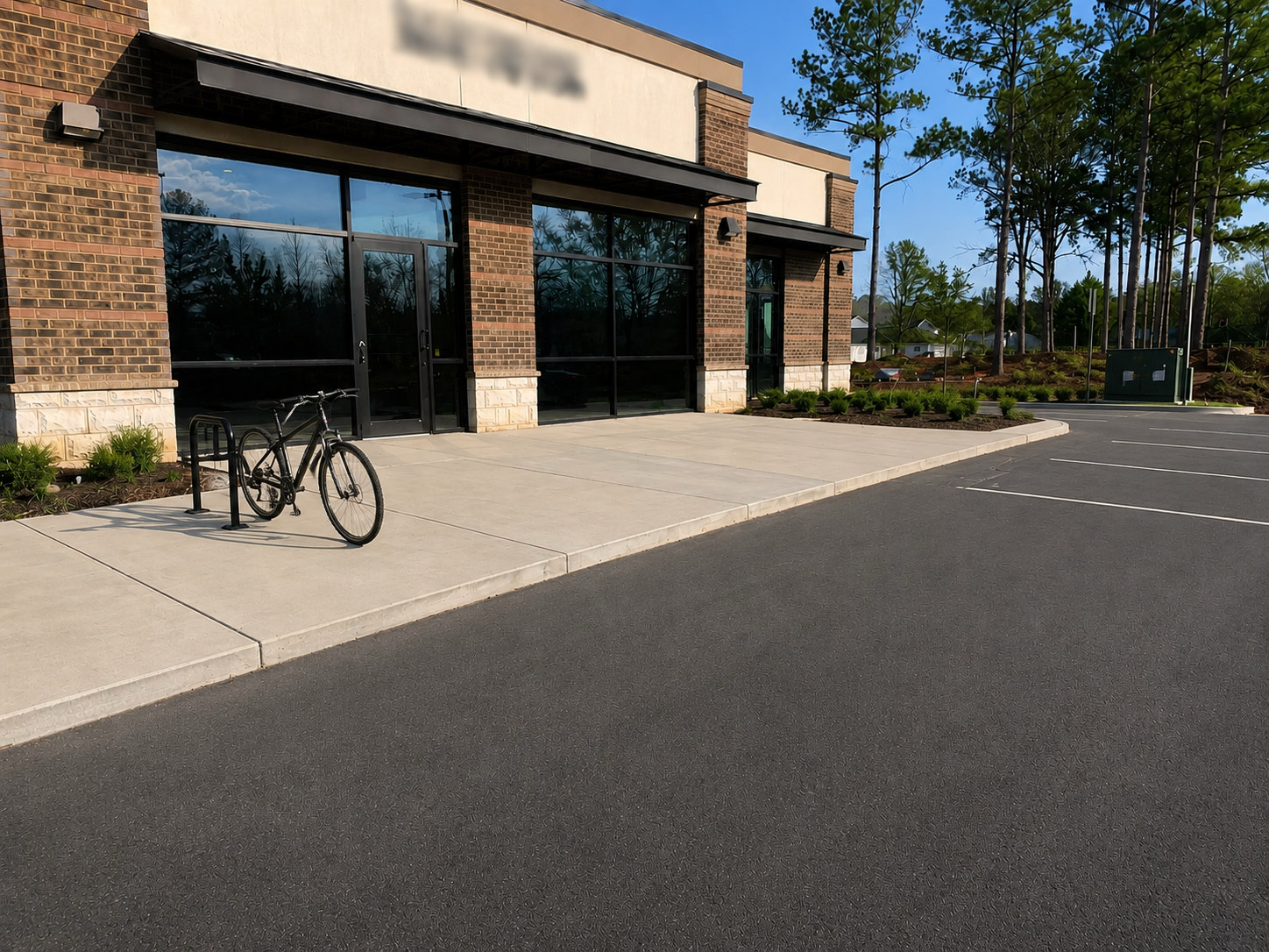Same storefront entry with clean concrete walkway and clear asphalt lot after red clay removal