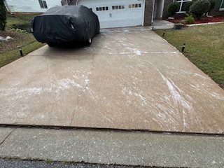 Driveway with cleaning solution on the surface in front of a garage.