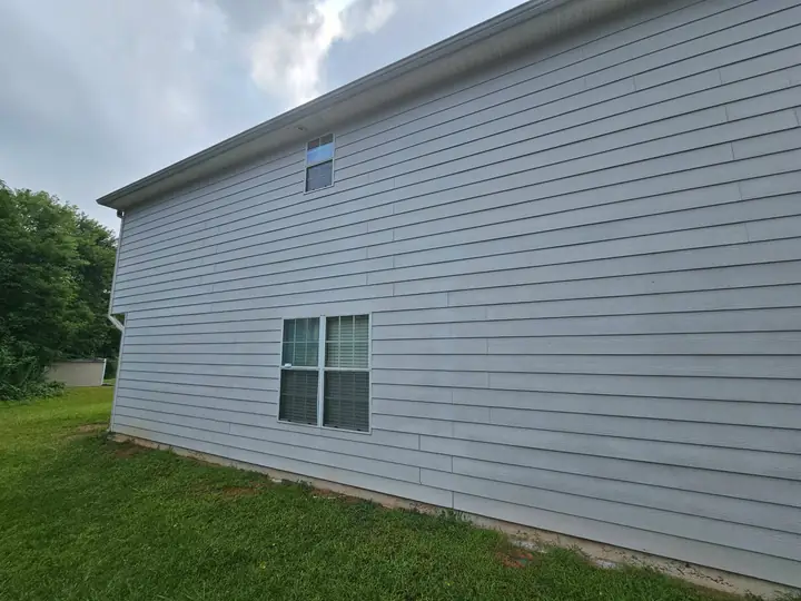 Freshly washed gray house siding with clean trim and windows beside a green lawn.