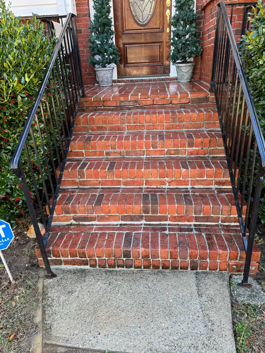 Red brick front steps and concrete landing after detailed pressure washing.