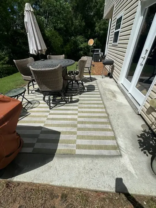 Backyard concrete patio with clean alternating sections beside outdoor furniture.