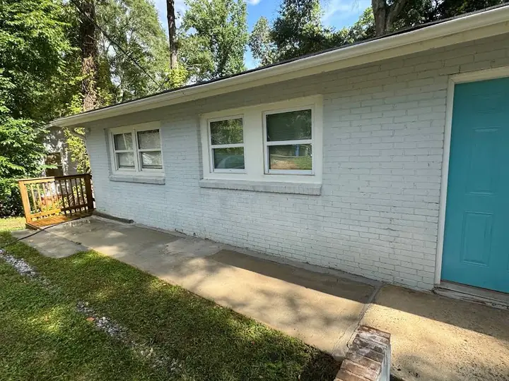 Freshly cleaned white painted-brick home exterior with bright trim and entry door.