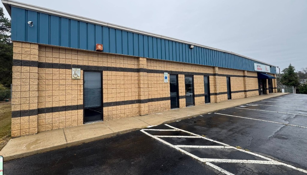 Commercial building with block and metal facade, storefront windows, and parking lot.